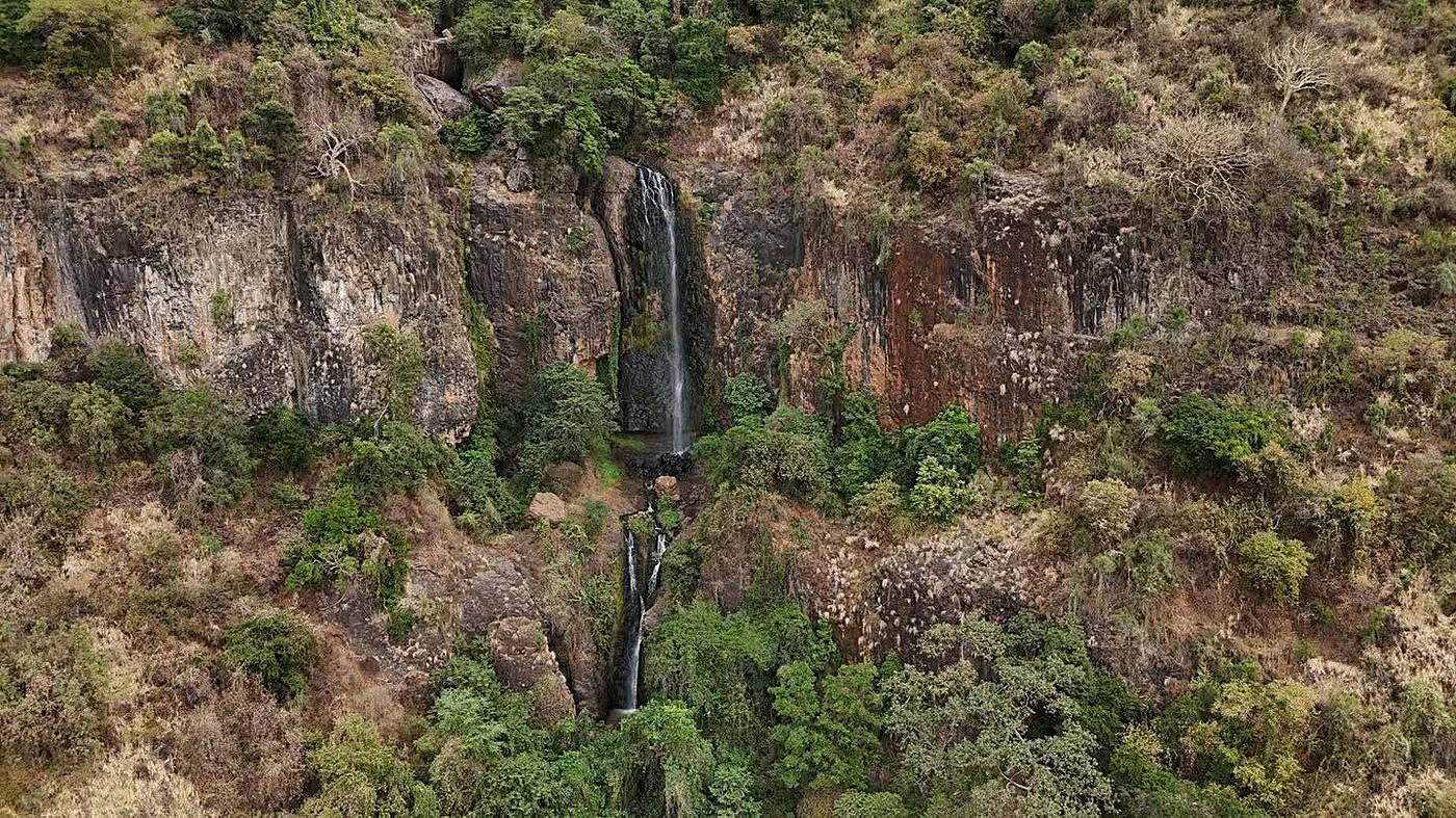 Aerial view of a waterfall dropping through the forested Nguruman Escarpment